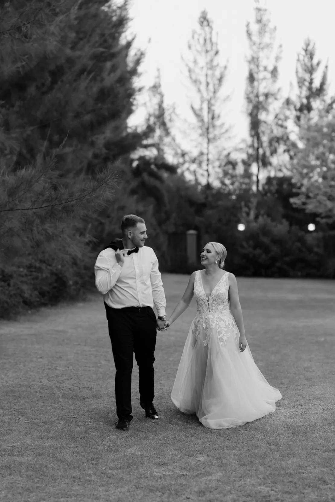 Bride and groom walking hand in hand through the forest in black and white, Pretoria wedding