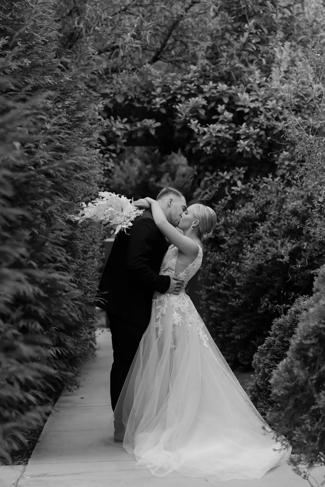 Bride and groom kissing amid greenery in black and white, Pretoria wedding